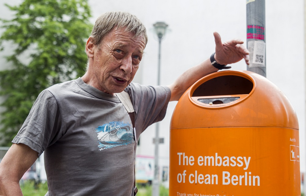 Klaus Seilwinder steht neben einem orangenen Mülleimer, wie sie überall in Berlin hängen.